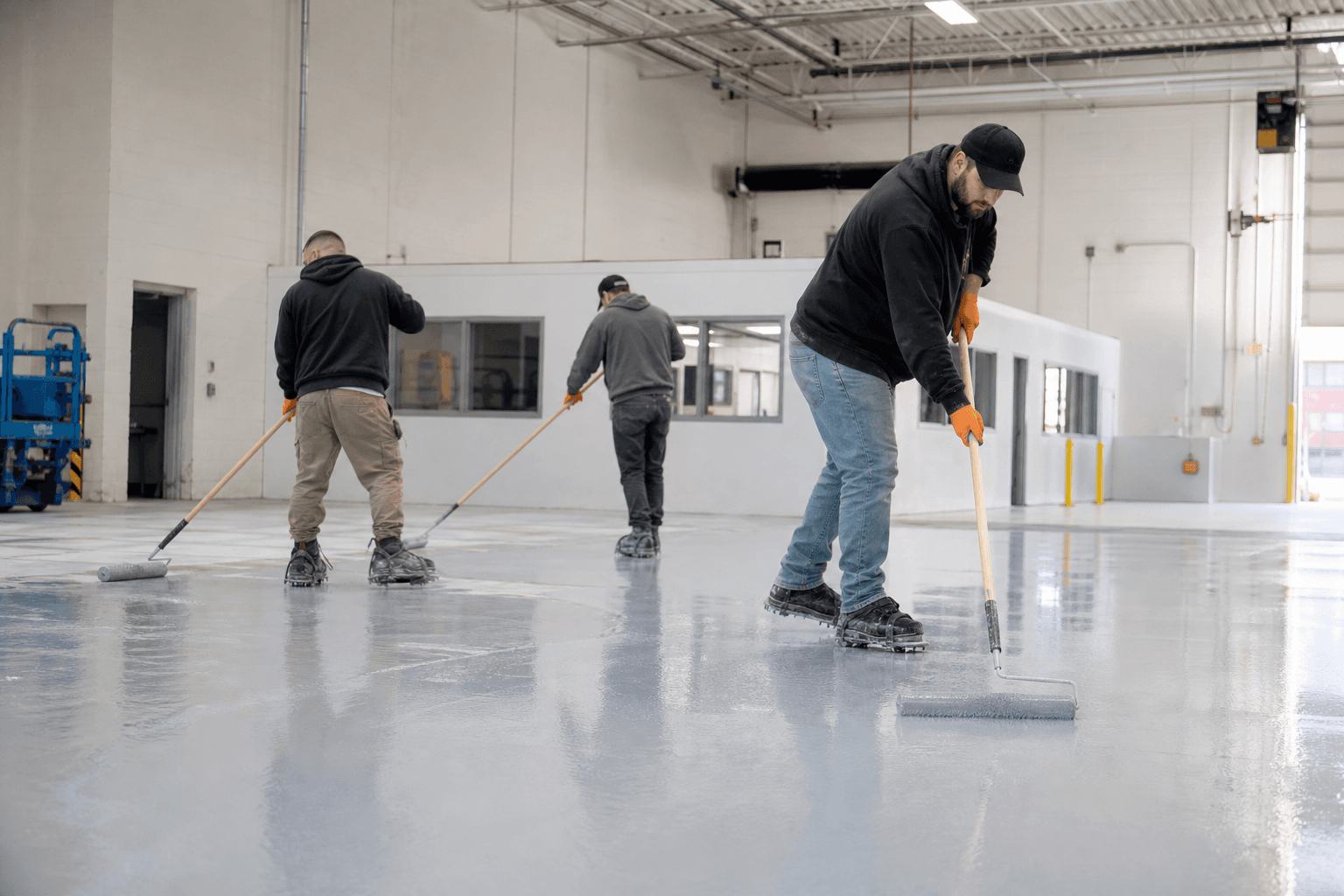 Crew applying epoxy base coat in a Troy commercial facility